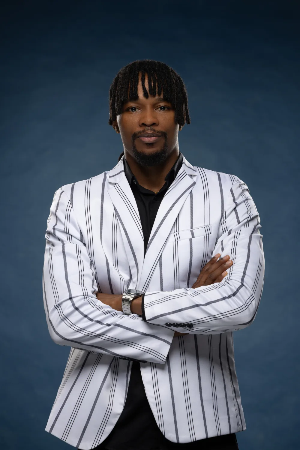 Ekene Eze facing the camera with arms folded in a striped blazer